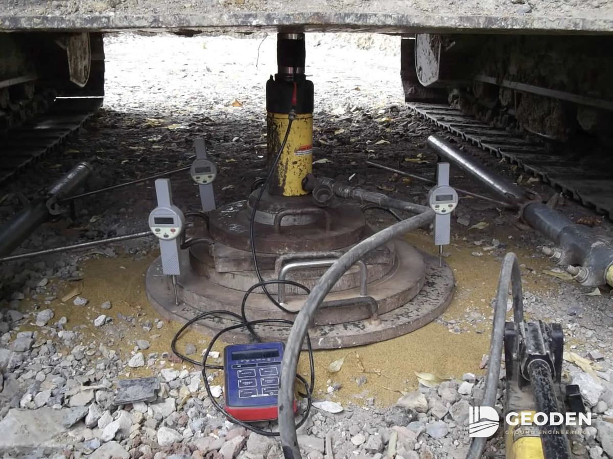 Plate load test set-up with jack, plate and dial gauges under a reaction load